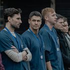 Eine Gruppe von Menschen, viele tragen blaues Krankenhauspersonal-Outfit mit Namensschildern um den Hals.