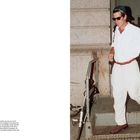 Text: "Opposite: The backward ball cap was one of JFK Jr.'s signature accessories..."
Ein Mann in Weiß, mit Rückwärtskappe und Sonnenbrille, steigt eine Treppe herab.