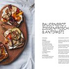 Bauernbrot mit Ziegenfrischkäse und Antipasti auf Brett, Rezept und Zutatenliste rechts mit Knoblauch, Gemüse, Brot.
