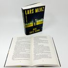 "Buch 'Der gute Sohn' von Lars Menz, Cover und aufgeschlagene Seiten, Thriller-Roman mit düsterem Covermotiv."