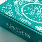 Der Text lautet "A CURSE FOR TRUE LOVE" auf einem türkisfarbenen Buchrücken mit weißen, dekorativen Mustern.
