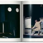 Links oben: "TATI SHOOTS", rechts oben: "MON ONCLE". Modernes Gebäude bei Nacht, Silhouetten und ein Mann öffnet ein Tor.