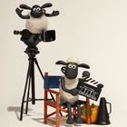 „Shaun the Sheep“, zwei Schafe aus Knetanimation. Eins sitzt mit Filmklappe, eins auf einer Kamera. Regiestuhl steht daneben.