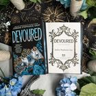 Zwei Bücher mit dem Titel "Devoured" von Jordan Stephanie Gray, umgeben von blauen Rosen und dekorativen Elementen.