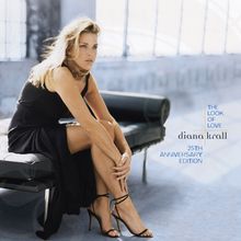 "The Look of Love, Diana Krall, 25th Anniversary Edition." Frau in schwarzem Kleid sitzt auf Sofa, heller Hintergrund.