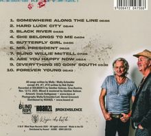 Setlist: "Somewhere Along the Line", "Hard Luck City" usw. Zwei Männer, einer trägt Hut, stehen lächelnd nebeneinander.