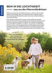"Rein in die Leichtigkeit, raus aus den Missverständnissen." Frau mit zwei Hunden läuft durch ein Sonnenblumenfeld.
