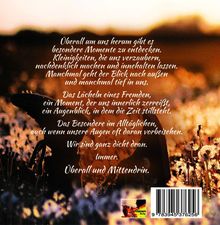 Ein Text beschreibt besondere Momente im Alltag. Im Hintergrund ist eine warme, goldene Landschaft mit Blumen zu sehen. Unten rechts befindet sich ein Barcode.