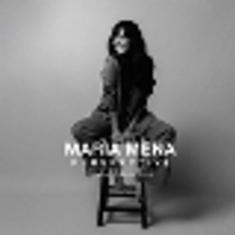 Text: "MARIA MENA | THEY NEVER LEAVE." Frau sitzt lächelnd auf einem Stuhl, Ambiente in Schwarz-Weiß.