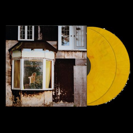 Zwei gelbe Schallplatten neben einem Foto eines Hauses mit großen Fenstern, durch die eine Person sichtbar ist.