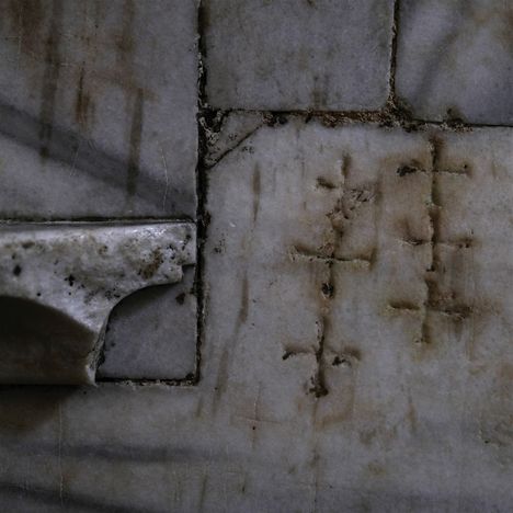Eingekerbte Kreuze in die Oberfläche eines alten, verwitterten Steins eingearbeitet, neben einer gebrochenen Kante.
