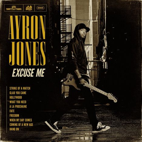 AYRON JONES. Excuse Me. Titel: Strike of a Match, Glad You Came. Ein Mann mit Gitarre in einer Gasse.