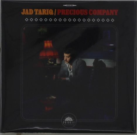 "JAD TARIQ / PRECIOUS COMPANY" oben, darunter ein Mann in einem Anzug sitzt nachdenklich in einem dunklen Raum mit einer Lampe.