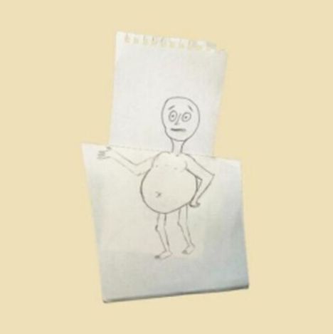 Eine einfache Zeichnung zeigt eine skizzierte, stehende Figur mit großem Bauch auf gefaltetem Papier.