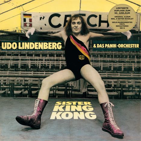 "Udo Lindenberg & Das Panik-Orchester" über einem Mann in Ringerpose im leeren Stadion. Goldene Stiefel, Anzug mit Flagge.