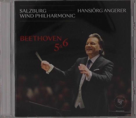 "Salzburg Wind Philharmonic, Hansjörg Angerer, Beethoven 5 & 6." Ein Dirigent in Aktion, lächelnd, mit erhobenem Taktstock.