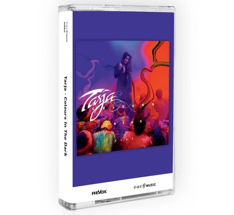 „Tarja; Colours in the Dark“. Eine Frau in einem dunklen Mantel, bunte Farben umgeben sie, mit vielen Menschen im Hintergrund.