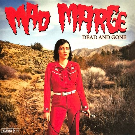 "Mad Marge Dead and Gone". Eine Frau in rotem Outfit hält ein Mikrofon in einer trockenen Landschaft.