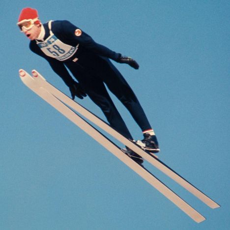 Die Zahl 58 auf einem Skispringer, der in der Luft schwebt. Der Himmel ist klar und blau.