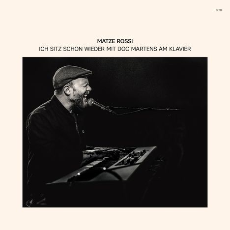 Text: "MATZE ROSSI ICH SITZ SCHON WIEDER MIT DOC MARTENS AM KLAVIER". Ein Mann mit Mütze singt und spielt Keyboard.