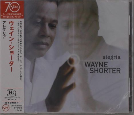 Text: "alegría, WAYNE SHORTER." Japanischer Text vertikal. Person berührt mit dem Finger eine strahlende Stelle.
