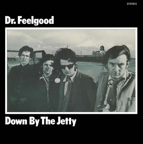 Text: "Dr. Feelgood", "Down By The Jetty". Schwarz-weißes Foto von vier Männern in Anzügen an einem Hafen.