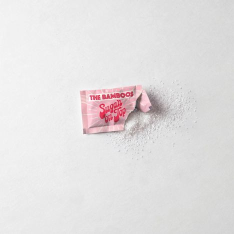 Text: "THE BAMBOOS Sugar on Top." Geöffneter rosa Zuckertütchen, Zucker rieselt heraus.