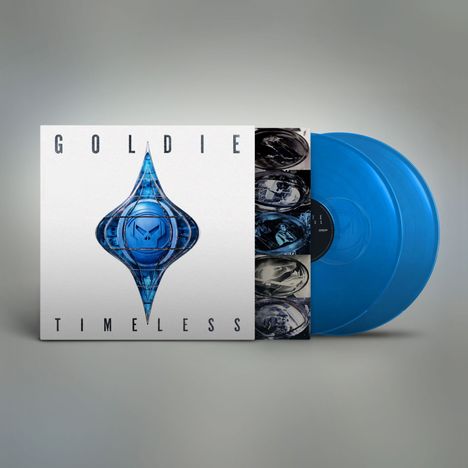 Text: G O L D I E, T I M E L E S S. Ein Albumcover mit blauem, skulpturalem Logo und zwei blauen Vinylplatten.