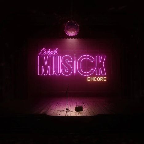 Neon-Schrift: "Lubach MUSICK ENCORE". Dunkle Bühne, Mikrofonständer, Diskokugel oben.