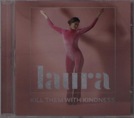 Text: "laura" und "KILL THEM WITH KINDNESS". Frau in pinkem Ganzkörperanzug hebt die Arme vor rosafarbenem Hintergrund.