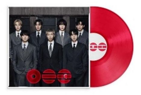 Text: „O O =“. Sieben Männer in Anzügen vor einem dunklen Hintergrund. Eine rote Vinylplatte ist daneben zu sehen.