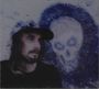 Keine Texte zu sehen. Ein Mann mit langem Haar und Baseballkappe vor einer blauen Totenkopf-Illustration.