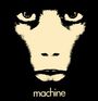 Text: "machine". Eine stilisierte Illustration eines Affengesichts mit eindringlichen Augen auf schwarzem Hintergrund.