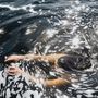 Ein Mensch taucht im Wasser, umgeben von Schaum und Sonnenreflexen auf der Wasseroberfläche.