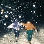 Zwei Personen laufen durch dichten Schneefall, nachts in einem verschneiten Gebiet, Hand in Hand.