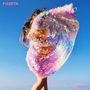 Text: "FUZETA" oben links, "Future" unten rechts. Frau in einem schillernden, bunten Umhang vor blauem Himmel.