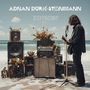 Text „ADNAN DURIĆ-STEINMANN“ und „ZEITGEIST“. Ein Musiker spielt Gitarre am Strand, umgeben von Verstärkern und Blumen.