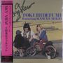 „SKY VIEW“, „TOKI HIDEFUMI featuring MASUDA MIKIO“. Eine Person sitzt zwischen Kindern auf Fahrrädern im Freien.