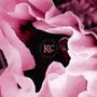 In der Mitte steht “K&C”. Dahinter eine Nahaufnahme einer rosafarbenen Blüte.