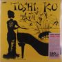 „Toshi“ und „Ko“ in großen Buchstaben. Silhouette einer Frau an einem Klavier, gelber Hintergrund, stilisierte Pflanzen.
