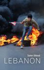 Text: Samer Abboud, LEBANON. Ein Junge springt mit einer libanesischen Flagge über brennende Reifen und Rauch.
