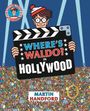 Ein Mann mit Brille und Mütze hält eine Filmklappe mit dem Text: "WHERE’S WALDO? IN HOLLYWOOD". Großer Menschenandrang.