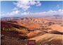 "Fuerteventura" in gelber Schrift, weite karge Landschaft mit sanften Hügeln unter einem blauen Himmel mit Wolken.