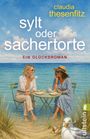 Text: "claudia thesenfitz, sylt oder sachertorte, EIN GLÜCKSROMAN." Zwei Frauen sitzen lachend am Tisch am Strand.