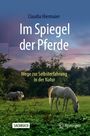 Buchtitel: "Im Spiegel der Pferde". Untertitel: "Wege zur Selbsterfahrung in der Natur". Zwei Pferde auf einer Wiese bei Sonnenuntergang.