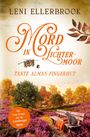 „Mord in Lichtermoor. Tante Almas Fingerhut.“ Herbstliche Landschaft mit Bank, Katze, und Büchern in der Heide.