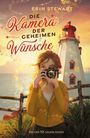 "Die Kamera der geheimen Wünsche" von Erin Stewart. Eine Frau mit Kamera vor Leuchtturm am Meer bei Sonnenuntergang.