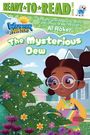 „The Mysterious Dew“: Mädchen mit Brille betrachtet glitzernde Blätter im Garten vor einem Haus, darunter bunte Blumen.