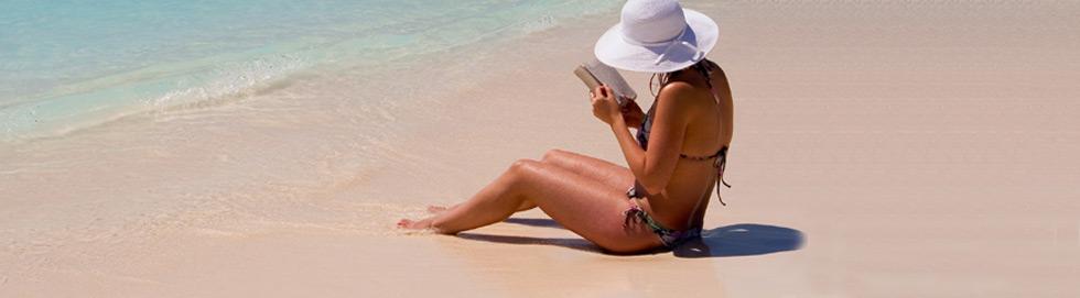 Frau mit Buch und weißem Hut am Strand unter der Sonne